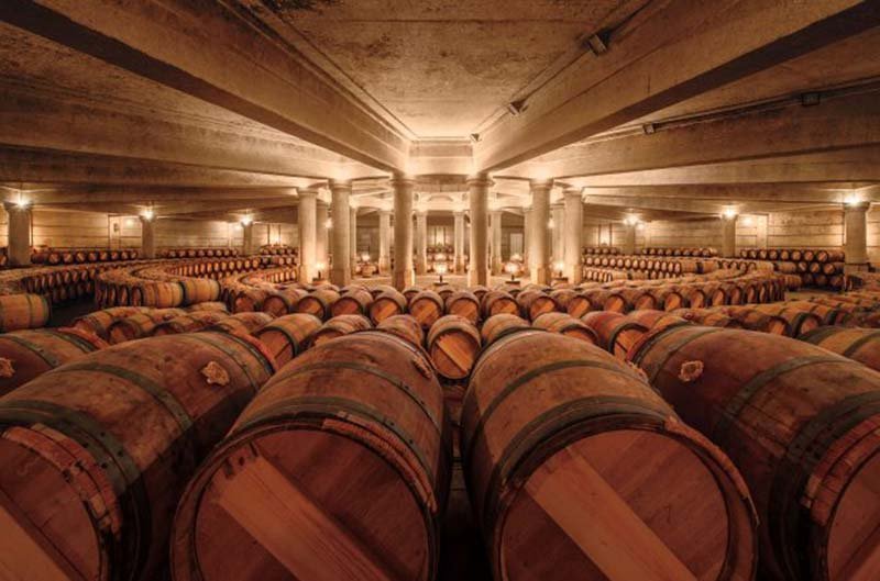 Cellar of Chateau Pichon Longueville with wine barrels.